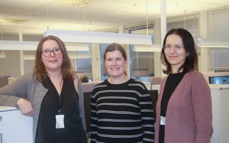tre kvinner står i et kontorlandskap